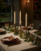 Styled illustration: ivory rechargeable taper candles in brass candlesticks on an autumn dinner table
